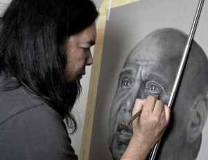 Artist Damien Shen works on his portrait of Archie Roach.